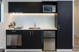 a kitchen with black cabinets and a microwave at Carnmore Hagley Park in Christchurch