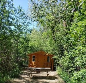 a wooden cabin with a picnic table and a bench at 11 Bridges Campground and Cabin Park in Rosedale