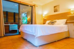 a bedroom with a large white bed and a bathroom at Sunbird Gardens in Agnes Water