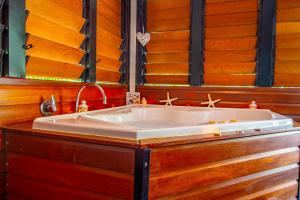 - une baignoire blanche dans une chambre dotée de murs en bois dans l'établissement Sunbird Gardens, à Agnes Water