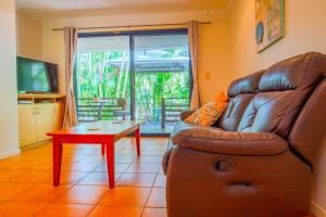 a living room with a leather couch and a table at Sunbird Gardens in Agnes Water