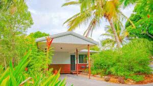 une petite maison avec des palmiers devant elle dans l'établissement Sunbird Gardens, à Agnes Water