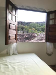 a bedroom with a window looking out at a field at Hostel Portal do Pati in Andaraí