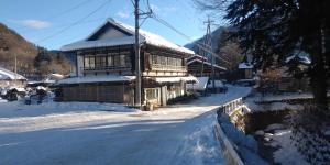 un antiguo edificio cubierto de nieve en un pueblo en Minpaku Sarai Nikkoya, en Okkia