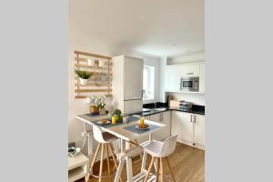 a kitchen with white cabinets and a table and chairs at Luna Beach - Luxury Carbis Bay Apartment + Parking in Carbis Bay