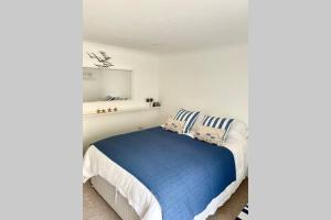a white bedroom with a bed with blue sheets at Luna Beach - Luxury Carbis Bay Apartment + Parking in Carbis Bay