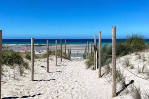 a beach with wooden poles in the sand and the ocean at Luna Beach - Luxury Carbis Bay Apartment + Parking in Carbis Bay