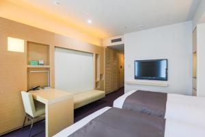 a hotel room with a bed, tv and a desk at Hotel Wing International Premium Shibuya in Tokyo