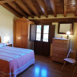 a bedroom with a bed and a dresser and windows at Casa Rural LA HUERTA DE POTES in Cabezón de Liébana