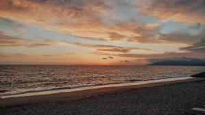 a sunset on a beach with the ocean at Casa Costa Suites in Kanali