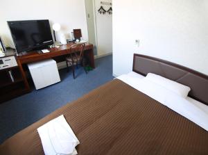 um quarto com uma cama, uma secretária e uma televisão em Royal Inn Kakegawa (Station Hotel 2) em Kakegawa