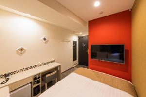 a bedroom with a red accent wall and a tv at Asta Hotel in Tokyo