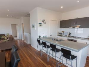 a kitchen with a counter with chairs and a kitchen island at Shearers Rest 5 Davey Road in Normanville