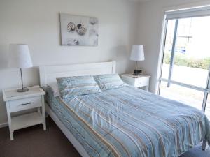 a bedroom with a bed with two night stands and two lamps at Shearers Rest 5 Davey Road in Normanville