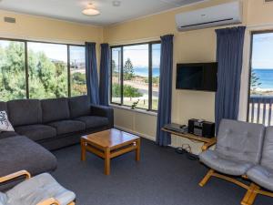 a living room with a couch and a tv and windows at Sandy Feet 31 Gold Coast Drive in Normanville
