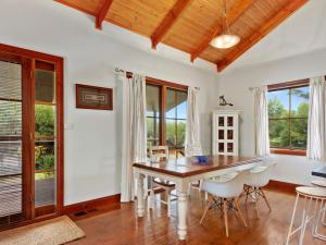 a dining room with a table and chairs and windows at 47 Jetty Road in Normanville