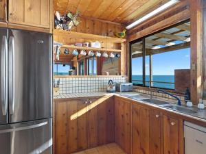 a kitchen with wooden cabinets and a stainless steel refrigerator at Cliffs End Beach Shack 105 Gold Coast Drive in Carrickalinga +22 photos