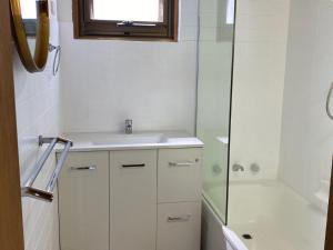 a white bathroom with a sink and a shower at Cliffs End Beach Shack 105 Gold Coast Drive in Carrickalinga