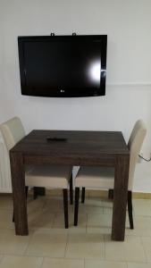 mesa de madera con sillas y TV en la pared en Agrino Hotel Apartments, en Ayia Napa