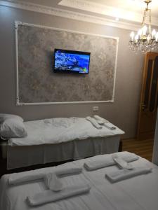 a room with two beds and a tv on the wall at HOTEL COMFORT in Kutaisi