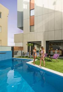 two women walking by a swimming pool at Hyperion City Hotel & Spa in Chania