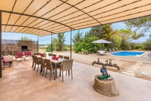 un patio con mesa, sillas y piscina en Finca Son Palanca en Sineu