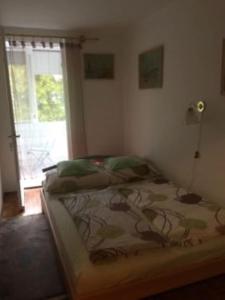 - une chambre avec un lit dans une pièce dotée d'une fenêtre dans l'établissement Lellei vízparti apartman homokos strandnál, à Balatonlelle