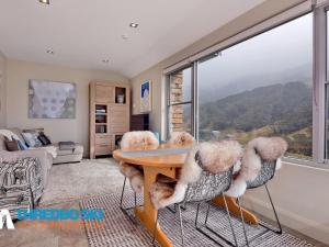 ein Wohnzimmer mit einem Tisch, Stühlen und einem Fenster in der Unterkunft The Peak 7 in Thredbo