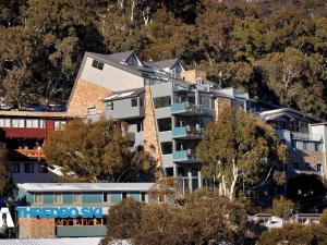 a building on a hill with trees in front of it at The Peak 7 in Thredbo