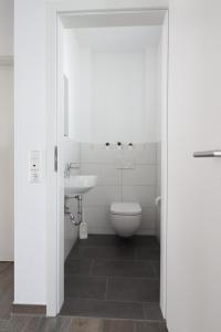 een witte badkamer met een toilet en een wastafel bij Ferienhaus im Angerdorf in Cuxhaven