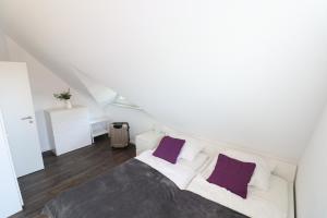 een witte slaapkamer met een bed met paarse kussens bij Ferienhaus im Angerdorf in Cuxhaven