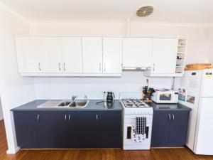 a kitchen with a sink and a stove and white cabinets at 20 Lady Bay Road in Normanville