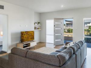 uma sala de estar com um sofá e uma televisão em Bungala Coastal Retreat 12 Nereus Drive em Normanville