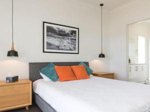 a bedroom with a bed with orange and blue pillows at Bungala Coastal Retreat 12 Nereus Drive in Normanville
