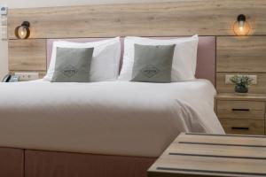 1 cama grande con almohadas blancas y cabecero de madera en Acropolis Vision, en Atenas