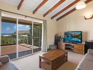 a living room with a television and a balcony at Footprints at Carrickalinga 31 Solitude Drive in Carrickalinga