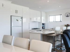 a kitchen with white cabinets and a table and chairs at 52 Turnberry Drive in Normanville