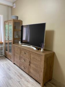 a wooden entertainment center with a flat screen tv on it at V15 Apartment in Druskininkai