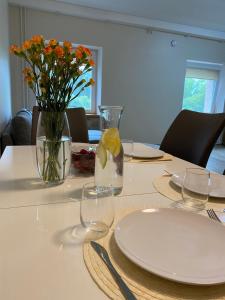 a table with plates and glasses and flowers in a vase at V15 Apartment in Druskininkai +12 photos