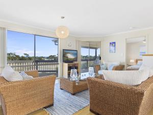 a living room with wicker chairs and a television at Carried Away 9 Dorset Court in Carrickalinga