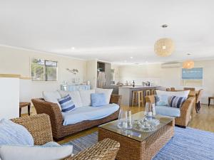 a living room with wicker furniture and a kitchen at Carried Away 9 Dorset Court in Carrickalinga