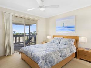 a bedroom with a bed and a balcony at Carried Away 9 Dorset Court in Carrickalinga