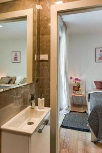 een badkamer met een wastafel en een spiegel en een slaapkamer bij Lunula Residence in Zadar