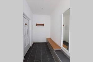 a hallway with white walls and a door and a wooden bench at FeWo Zum Schloss in Weißenfels +1 photo
