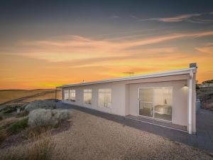 a white house with a sunset in the background at Fleurieu Coastal Retreat Lot 150 Myponga Beach in Wattle Flat