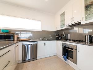 una cocina con armarios blancos y electrodomésticos de acero inoxidable en Fleurieu Coastal Retreat Lot 150 Myponga Beach, en Wattle Flat