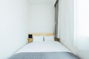 a bed in a small room with white walls at Hotel Nupka in Obihiro