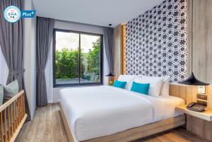 a bedroom with a large bed and a window at The Lake Chalong Hotel SHA Plus in Chalong