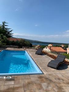 a swimming pool on a patio with two lounge chairs at Lili Apartments, Sv Dunata 18 in Krk