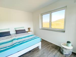 a white bedroom with a bed and a window at Wunderschöne helle Wohnung mit großer Dachterrasse in Gottmadingen